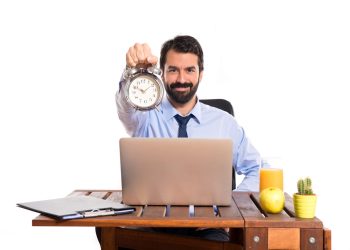 Businessman in his office holding a clock
